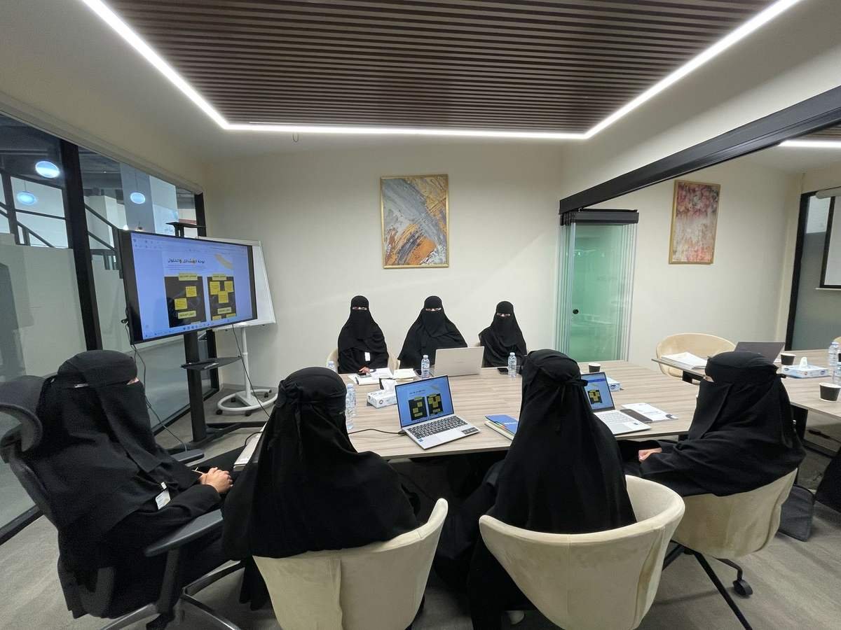 مشاركون يعملون على لوحة المشاكل والحلول المعروضة على الشاشة وأجهزتهم الشخصية.